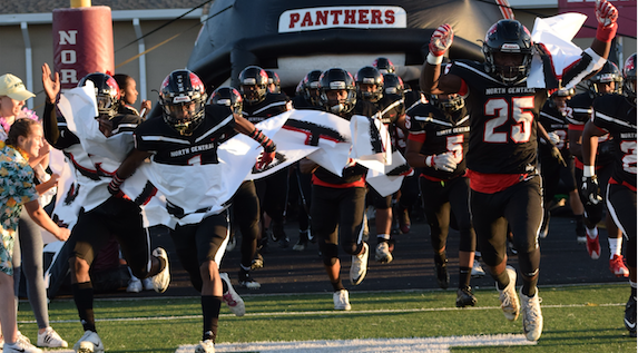 The football team beat Fishers last year. The team runs out on to the field. 