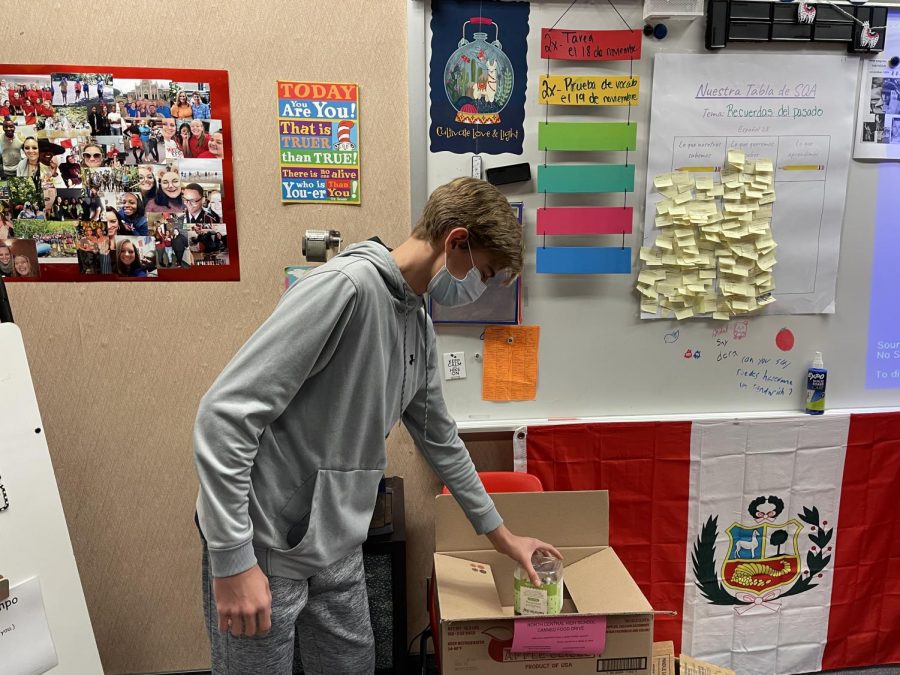 Freshman Max Baltz donates to the canned food drive during period one. Most classes around the school have canned food donation boxes, allowing the students to donate their items at any time.