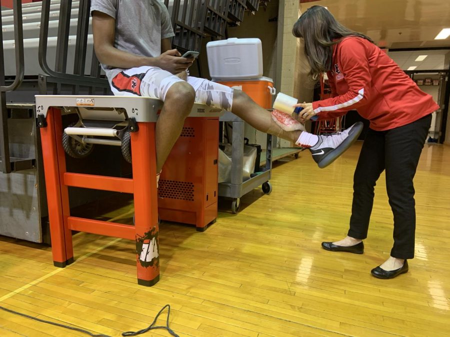Athletic+trainer+Miho+Sayles+wraps+up+an+athlete+prior+to+their+game.+Sayles+is+one+of+the+athletic+trainers+that+helps+injured+student+athletes+and+helps+them+prevent+further+injuries.+