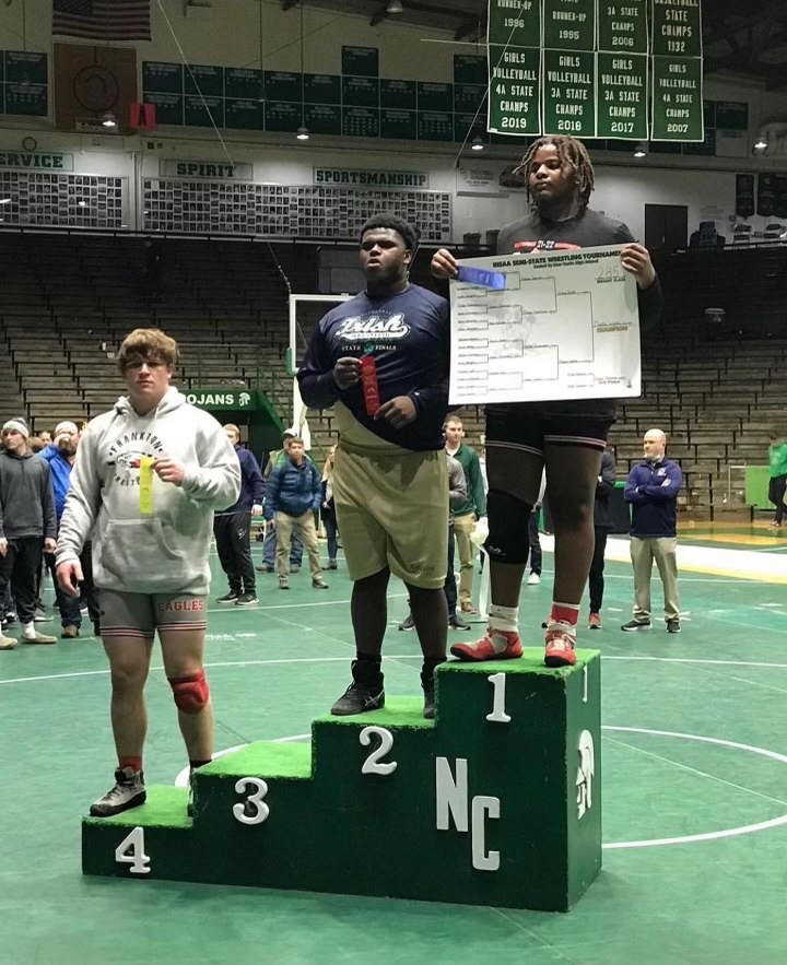 Senior Makhi Watts stands on the podium at the semi-state wrestling competition. 