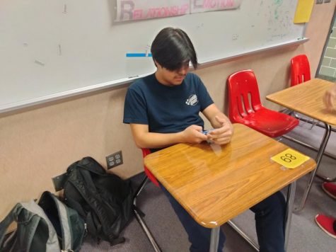A junior checks his phone during class.