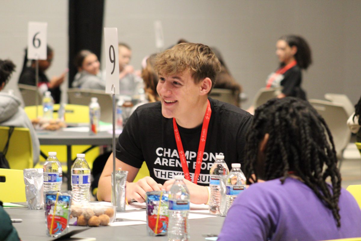 Senior Caleb Foor gets to know his table group of middle schoolers before the event starts. Groups stayed together for both speeches and participated in service projects together. 