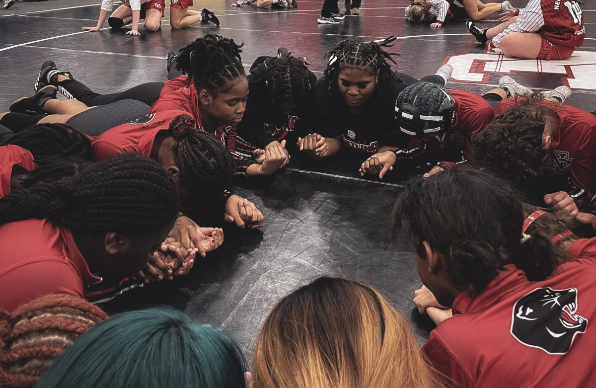 Girls wrestling team joins hands in preparation for the senior night competition. This was a tradtition to start off each match day of the season.