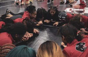 Girls wrestling team joins hands in preparation for the senior night competition. This was a tradtition to start off each match day of the season.