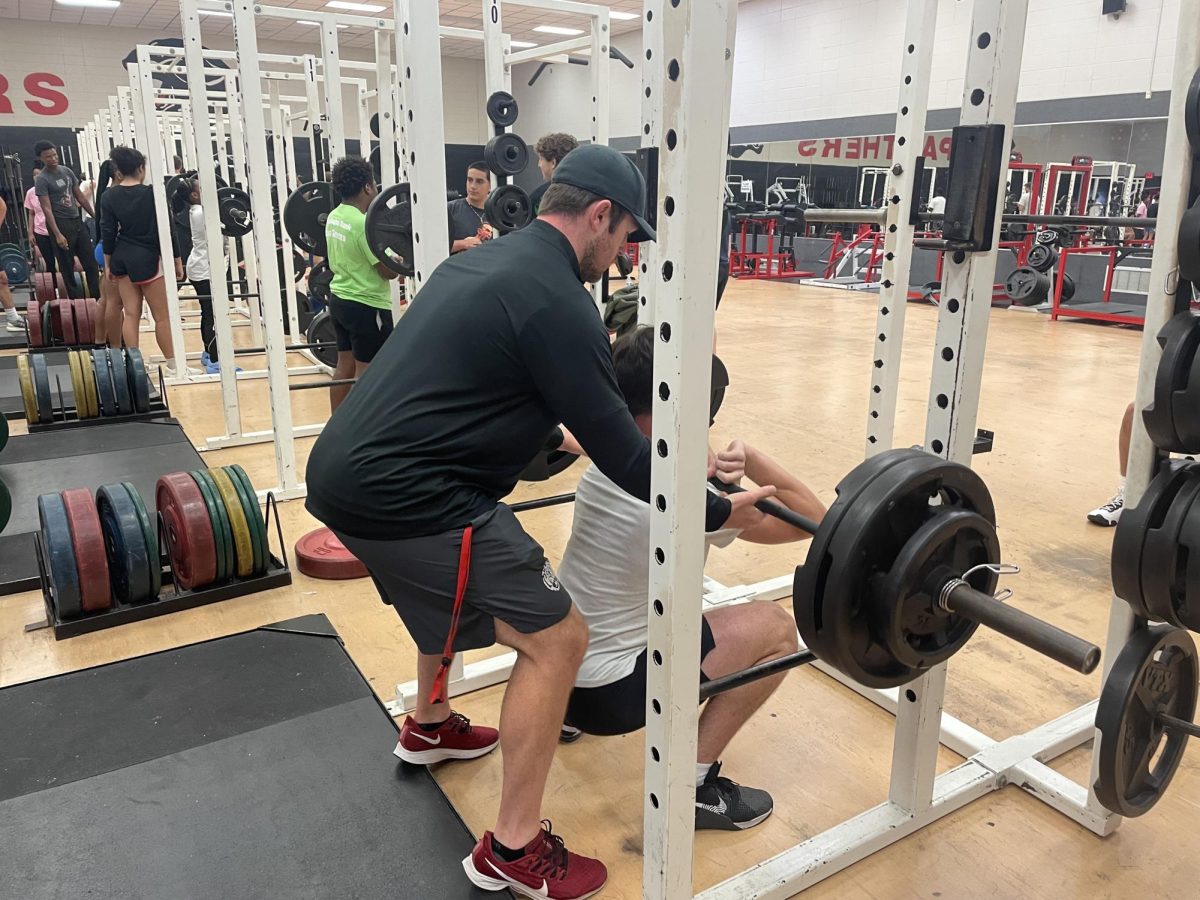 Senior Max Roberts performs front squat with Coach Conor Andras spotting him.