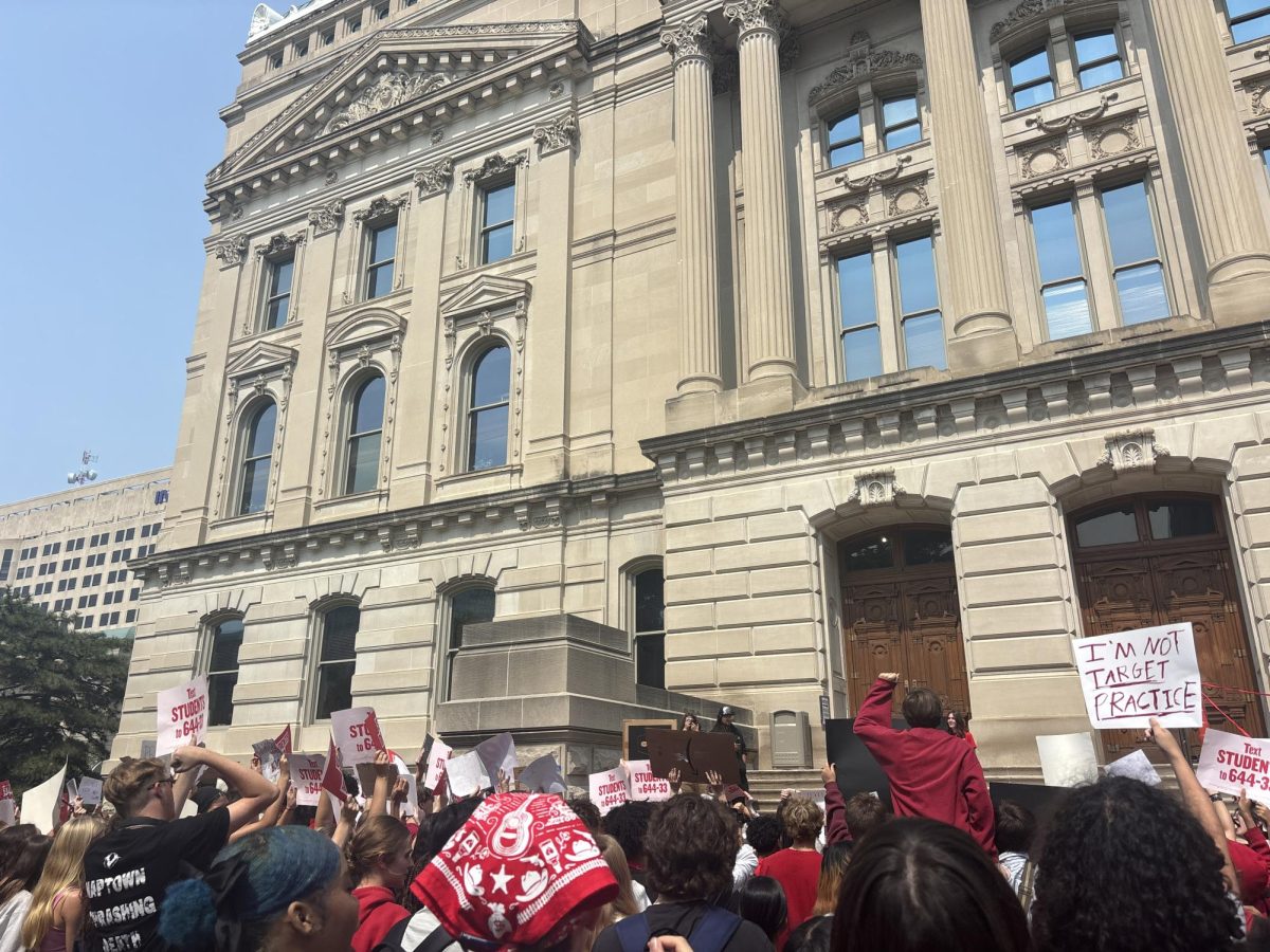 Students and adults hold signs and chant outside the state house to show their support for anti-gun violence speakers.
