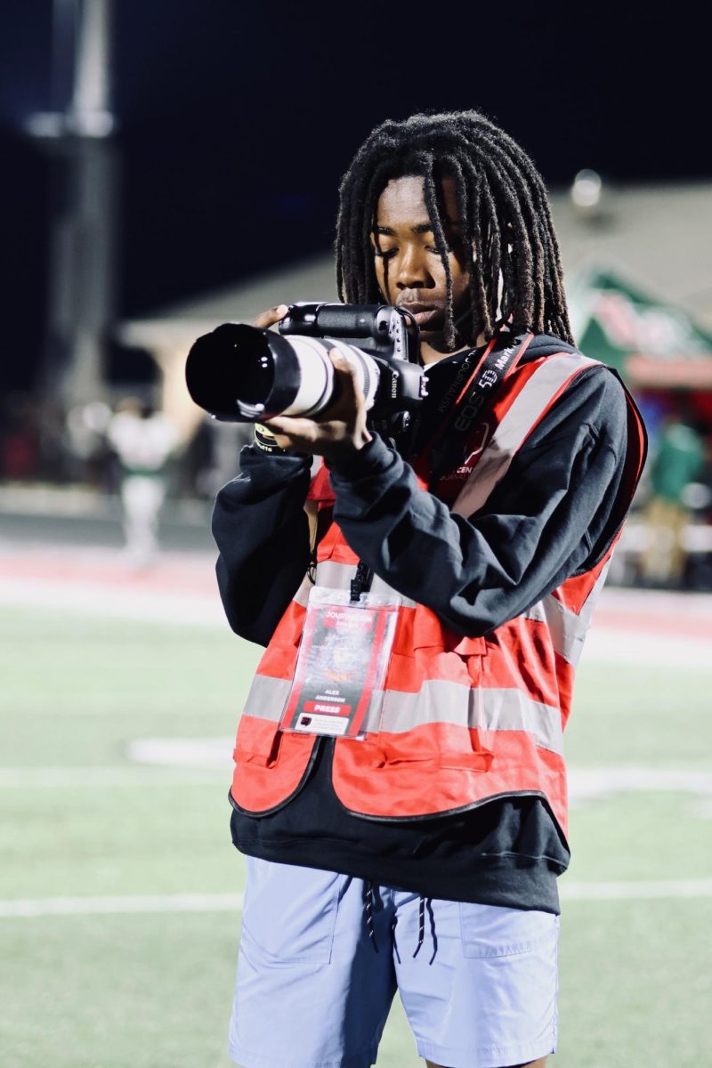 Sophmore Alex Anderson shoots at the football game against Lawerence North high school. Anderson took intro to photography his freshman year and now shoots for student media,