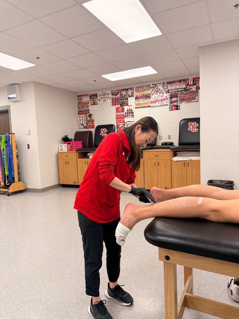 Athletic trainer Miho Sayles working on an athletes ankle after practice. Many athletes go to Sayles to get help for injuries or to work on strechting. “You can’t just go home and do nothing. Drink water, eat, and get enough sleep,” Sayles said.
