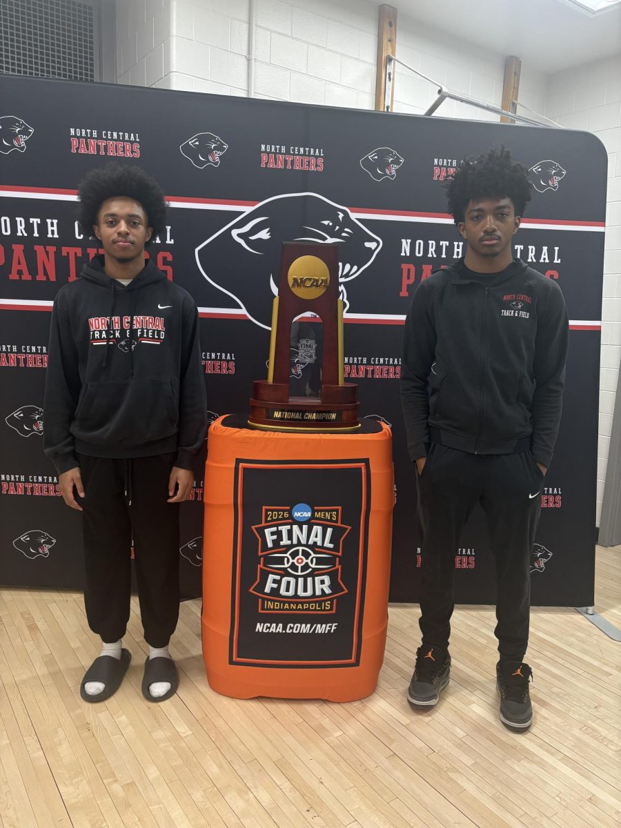 Junior Brennen Bembry and sophomore Brenton Phillips posing with the NCAA Men's Basketball National Championship trophy. The trophy was brought to North Central and students got the opportunity to get a picture with the trophy.