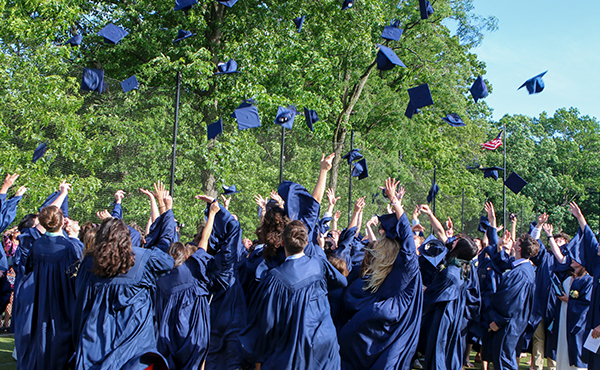 This photo shows college graduates throwing their caps into the air at their ceremony.
